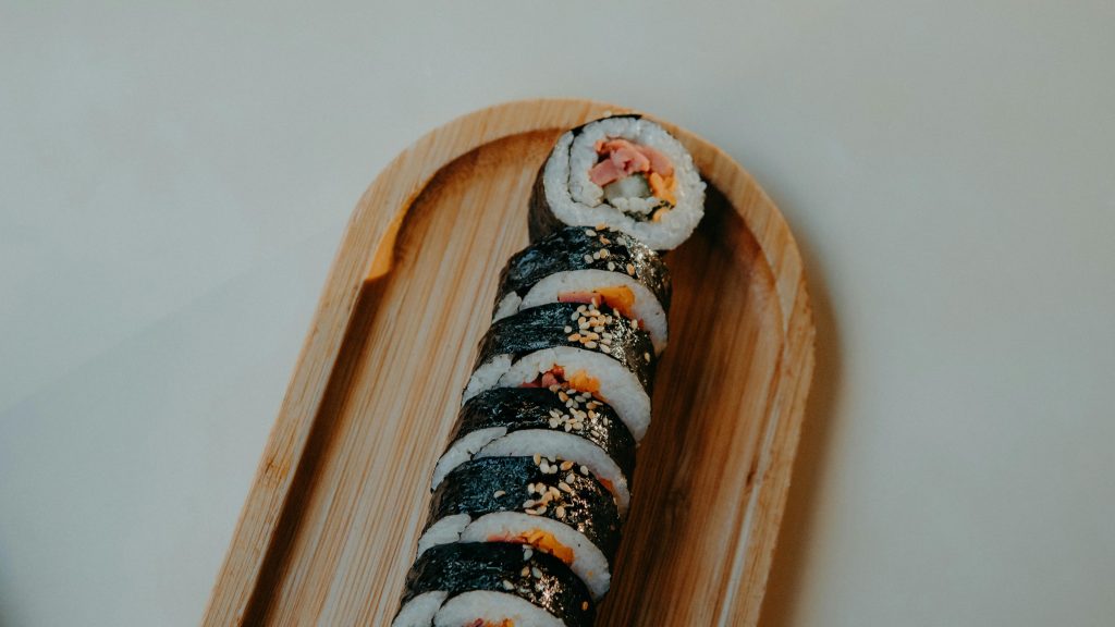 Sushi roll with sesame seeds presented on a bamboo tray. Perfect for culinary and food themes.